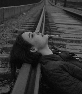 sad girl image lying on railway track